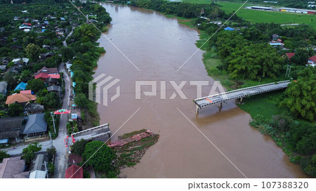 Aerial view of a damaged road bridge over a river after floodwaters washed away the asphalt. Broken bridge after flash floods in the rainy season. Aerial view of a damaged road bridge over a river after floodwaters washed away the asphalt. Broken bridge after flash floods in the rainy season. 107388320