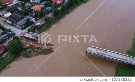 Aerial view of a damaged road bridge over a river after floodwaters washed away the asphalt. Broken bridge after flash floods in the rainy season. Aerial view of a damaged road bridge over a river after floodwaters washed away the asphalt. Broken bridge after flash floods in the rainy season. 107388322