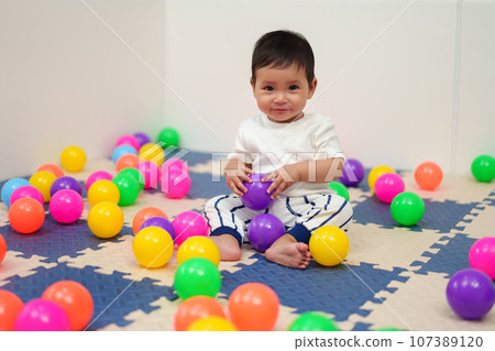 happy infant baby playing colorful balls in playpen happy infant baby playing colorful balls in playpen 107389120