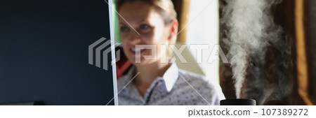 Humidifier with rising steam on desk of office employee 107389272