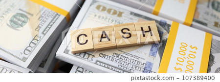 Wooden square blocks in form of word Cash on pack of dollars Wooden square blocks in form of word Cash on pack of dollars 107389400