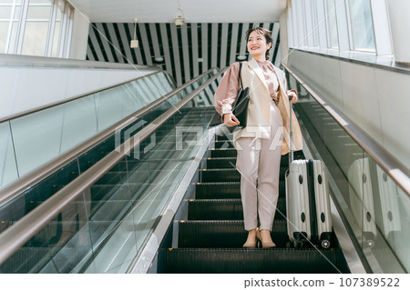 Business woman on a business trip climbing up the escalator at the airport/station (commuting/commuting) Business woman on a business trip climbing up the escalator at the airport/station (commuting/commuting) 107389522