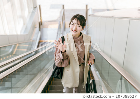 海外出差的女商人在機場/車站的自動扶梯上揮手（海外旅行、會議、通勤） 107389527