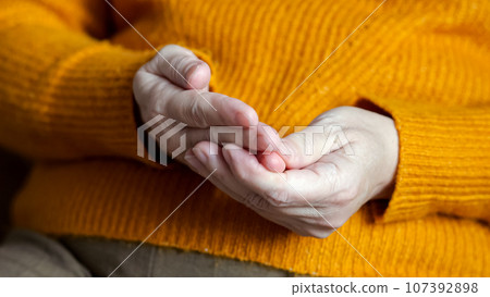 Mature woman touches fingers on hand with unsure actions 107392898