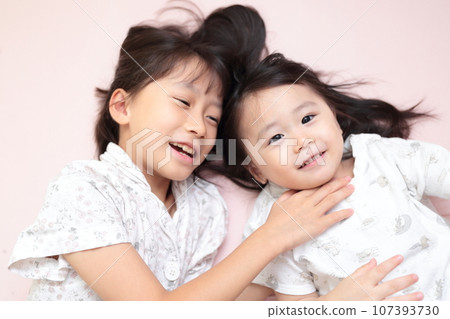 Close sisters playing while lying on the bed Close sisters playing while lying on the bed 107393730