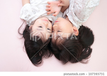 Close sisters playing while lying on the bed 107393731