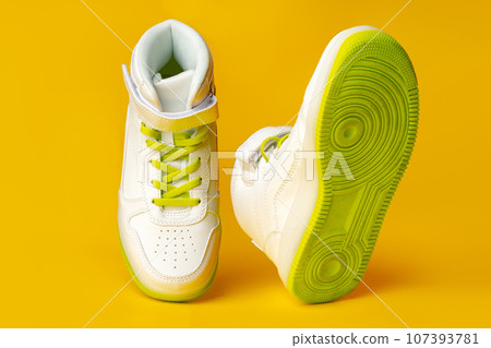 White sneakers with yellow neon laces on yellow background White sneakers with yellow neon laces on yellow background 107393781