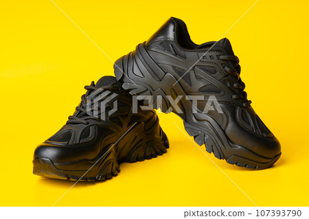 Black new sport sneakers on yellow background Black new sport sneakers on yellow background 107393790