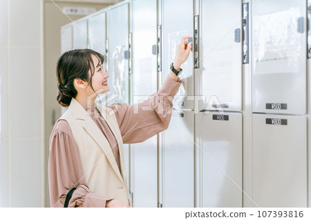 一位女士將行李寄存在車站或商業設施的投幣式儲物櫃中 一位女士將行李寄存在車站或商業設施的投幣式儲物櫃中 107393816