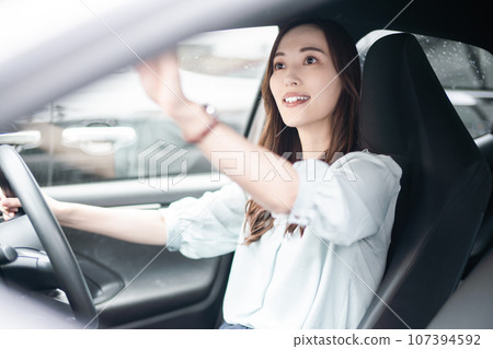 Young woman in business casual clothes checking the rearview mirror Young woman in business casual clothes checking the rearview mirror 107394592