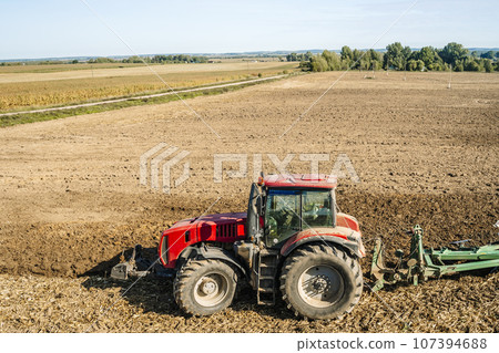 Tractor in the field. Agricultural machinery. Agricultural farm tractor during tillage of soil and field after harvest. 107394688
