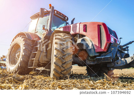 Tractor in the field. Agricultural machinery. Agricultural farm tractor during tillage of soil and field after harvest. 107394692