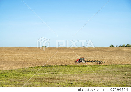 Tractor in the field. Agricultural machinery. Agricultural farm tractor during tillage of soil and field after harvest. Tractor in the field. Agricultural machinery. Agricultural farm tractor during tillage of soil and field after harvest. 107394724