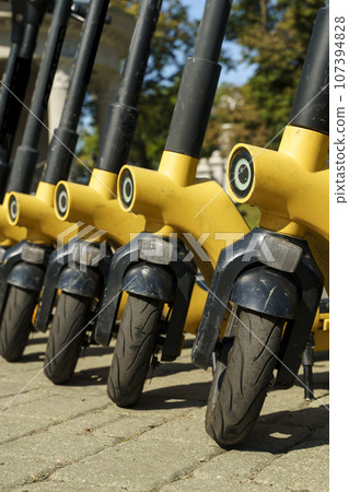 Electric scooters for rent on the city street. Eco-friendly electric scooter rental service. 107394828