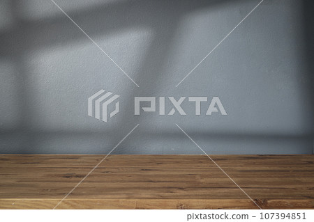 Table shadow background. Wooden table and white empty wall with plant shadows. 107394851