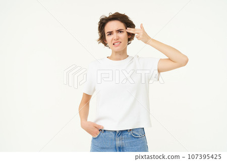 Portrait of woman holding fingers near temple, beeing fed up, annoyed by something, standing tired against white background 107395425