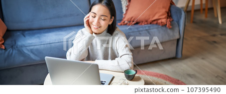 Beautiful asian girl works from home, studying with laptop, sitting in living room, being on remote, freelancing online 107395490