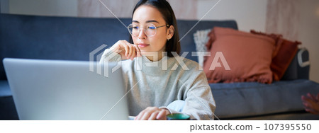 Portrait of smiling asian girl working from home, staying on remote, using laptop, studying on her computer 107395550