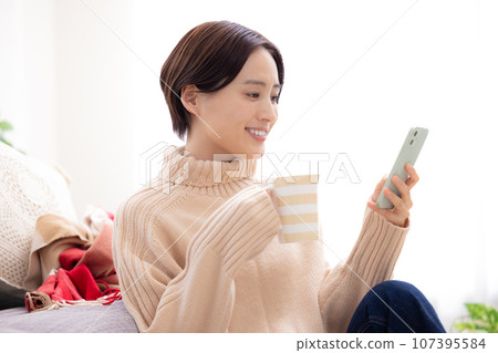 一個女人在客廳裡看著她的智能手機 107395584