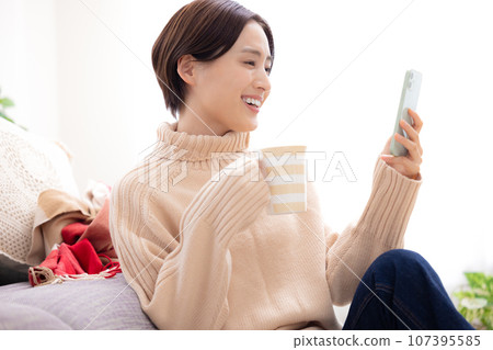 一個女人在客廳裡看著她的智能手機 107395585