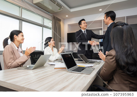 Happy businessman shaking hands at group board meeting. Professional business executive leaders trade partnership handshake concept. 107395963