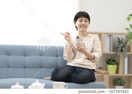 坐在沙發上使用智能手機的年輕女性 107395981