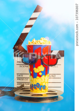 Movie clapper, pop corn, 3D glasses and film reel on blue background. Collage design Movie clapper, pop corn, 3D glasses and film reel on blue background. Collage design 107396807