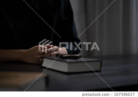 Closeup of simple wooden Christian cross on Bible. Concept of hope, faith, christianity, religion. Closeup of simple wooden Christian cross on Bible. Concept of hope, faith, christianity, religion. 107396817