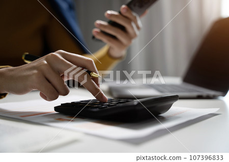 Hand business woman doing finances and calculate on desk about cost at office. Hand business woman doing finances and calculate on desk about cost at office. 107396833