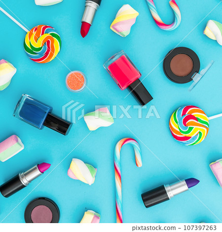 Cosmetics and bright candy on blue background. Top view. Flat lay. Creativity feminine desk. Cosmetics and bright candy on blue background. Top view. Flat lay. Creativity feminine desk. 107397263