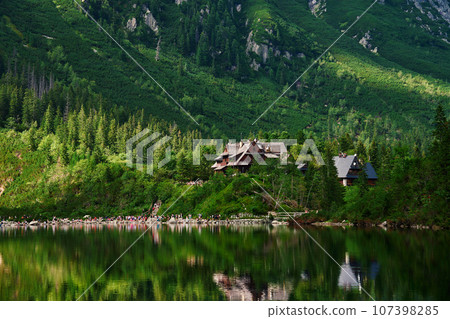View on cabin in mountains with green forest. House for tourists in Tatra National Park near Morskie Oko or Eye Sea lake. Touristic place in Poland 107398285