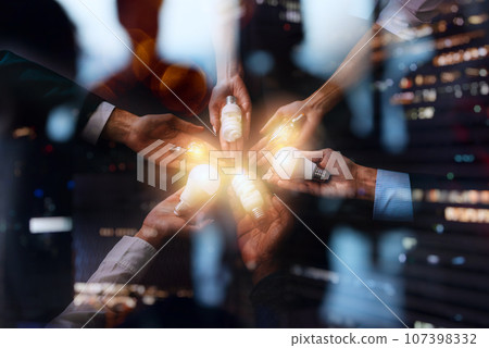 Teamwork and brainstorming concept with businessmen that share an idea with a lamp Teamwork and brainstorming concept with businessmen that share an idea with a lamp 107398332