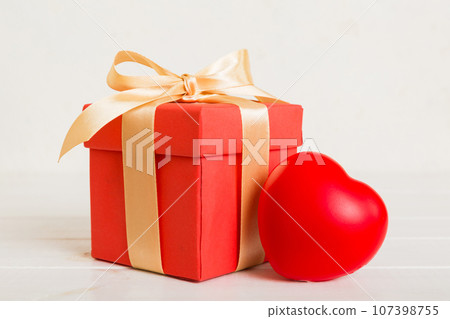gift box with red bow and red heart on colored background. Perspective view. Flat lay 107398755