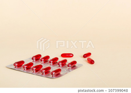 Blister package with Vitamin a on color background. Medicine pills on a light background. Medicines and prescription pills flat lay background. red medical tablets in blister Blister package with Vitamin a on color background. Medicine pills on a light background. Medicines and prescription pills flat lay background. red medical tablets in blister 107399048