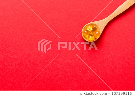 Vitamin omega capsules in a spoon on a colored background. Pills served as a healthy meal. Red soft gel vitamin supplement capsules on spoon Vitamin omega capsules in a spoon on a colored background. Pills served as a healthy meal. Red soft gel vitamin supplement capsules on spoon 107399116