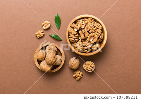Walnut kernel halves, in a wooden bowl. Close-up, from above on colored background. Healthy eating Walnut concept. Super foods with copy space 107399211