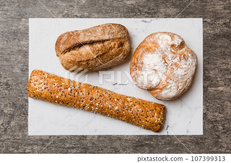 Assortment of freshly baked bread with napkin on rustic table top view. Healthy unleavened bread. French bread 107399313