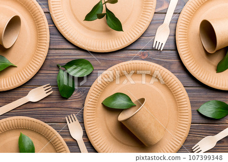 set of empty reusable disposable eco-friendly plates, cups, utensils on light white colored table background. top view. Biodegradable craft dishes. Recycling concept. Close-up set of empty reusable disposable eco-friendly plates, cups, utensils on light white colored table background. top view. Biodegradable craft dishes. Recycling concept. Close-up 107399348