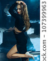 Sexy fashionable lady in black dress posing in studio on dark foil background 107399963