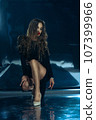 Sexy fashionable lady in black dress posing in studio on dark foil background 107399966