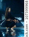 Sexy fashionable lady in black dress posing in studio on dark foil background 107399968