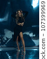 Sexy fashionable lady in black dress posing in studio on dark foil background 107399969
