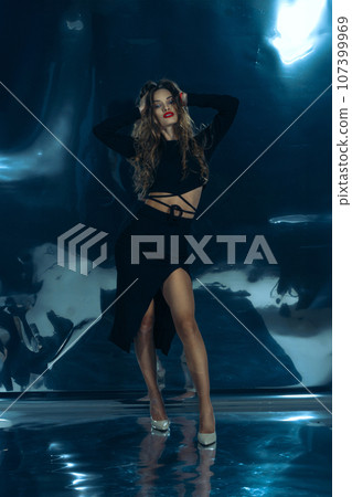 Sexy fashionable lady in black dress posing in studio on dark foil background 107399969