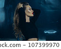 Sexy fashionable lady in black dress posing in studio on dark foil background 107399970