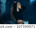 Sexy fashionable lady in black dress posing in studio on dark foil background 107399971
