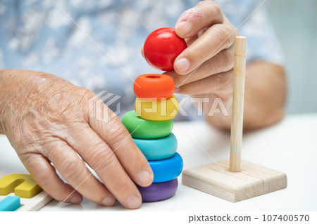 Alzheimer disease AD, Asian elderly woman patient suffering from dementia learn practical motor skills rehabilitation. Alzheimer disease AD, Asian elderly woman patient suffering from dementia learn practical motor skills rehabilitation. 107400570