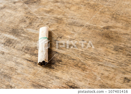 Cigarette butt discarded outdoors on the wooden table 107401416