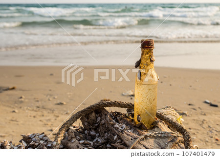 old disused beverage bottle on the beach 107401479