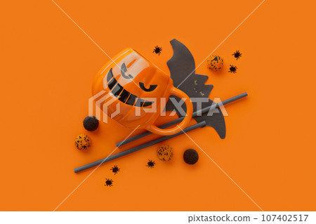 Pumpkin cup, gummy, straws, bat napkin on orange background. Halloween celebration concept Pumpkin cup, gummy, straws, bat napkin on orange background. Halloween celebration concept 107402517