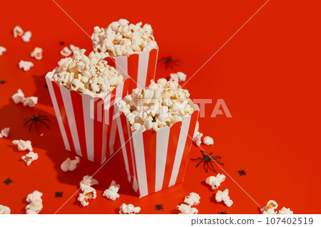 Striped boxes with popcorn on a red background 107402519